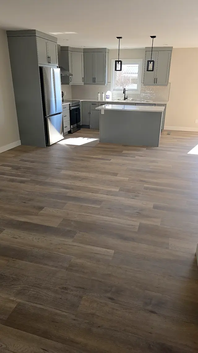 Open kitchen with pendant lights and wide plank flooring